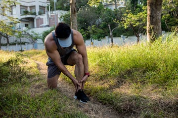 a asian runner pauses and massages his leg to alleviate pain from shin splints common running injury