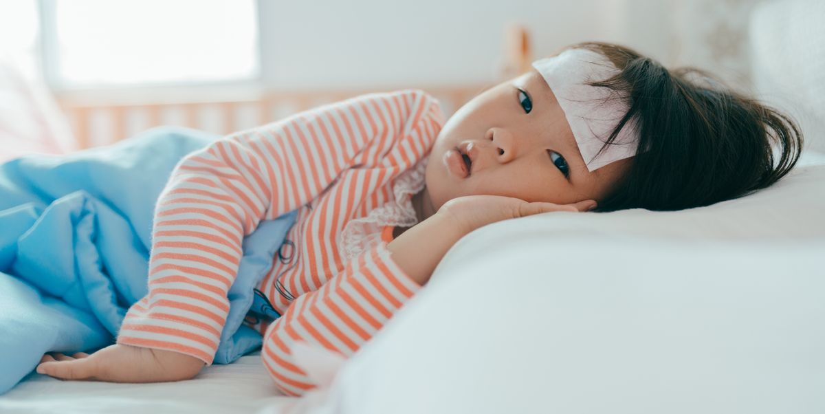 Asian sick little girl lying in bed with a high fever