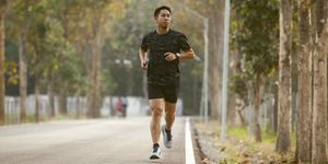 asian sportman jogging and checking smart watch between workout jogging outdoor