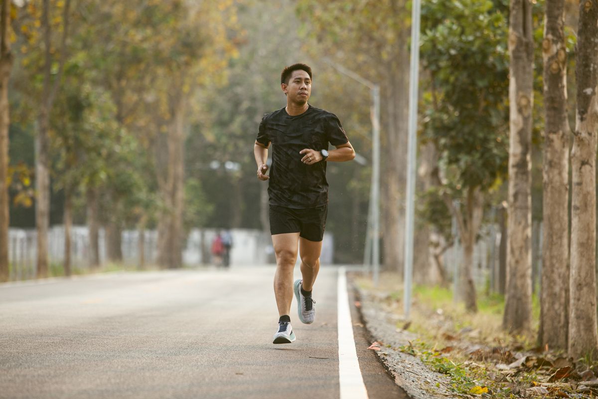 asian sportman jogging and checking smart watch between workout jogging outdoor