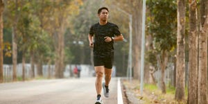 asian sportman jogging and checking smart watch between workout jogging outdoor