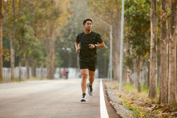 asian sportman jogging and checking smart watch between workout jogging outdoor