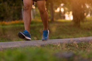 asian sporty man running on countryside road with sunset and flare