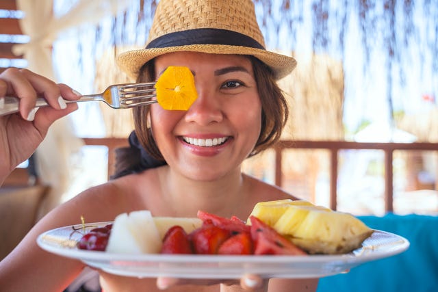 una mujer toma un plato de fruta en un chiringuito