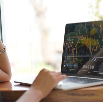 asian woman looking stock market graph at monitor screen