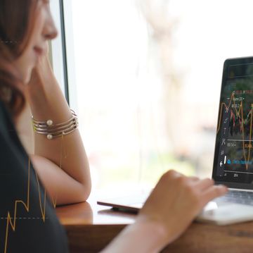 asian woman looking stock market graph at monitor screen