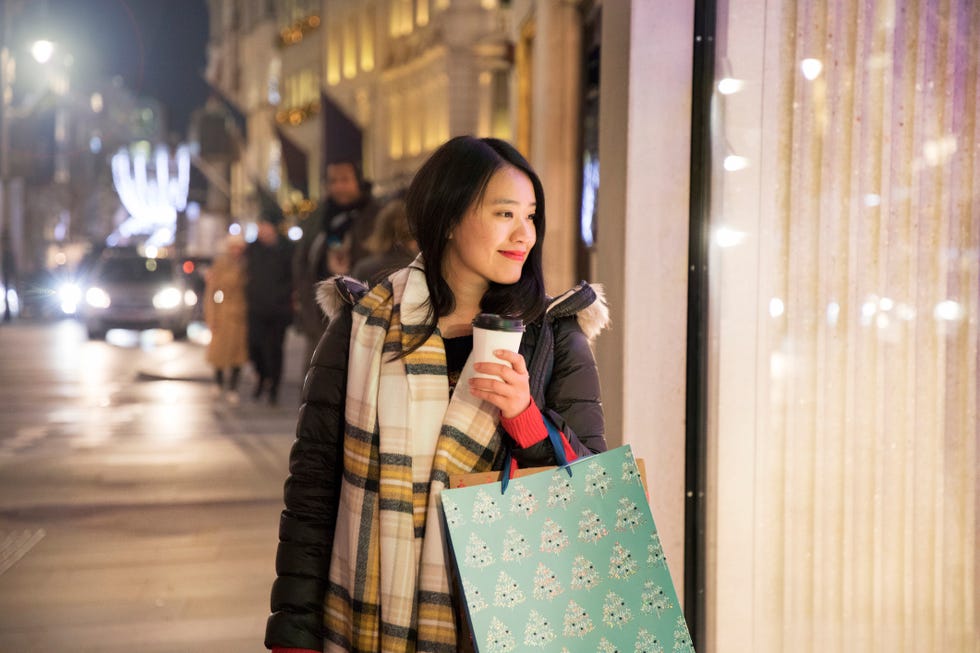 Asian woman shopping, looking in shop window while walking.