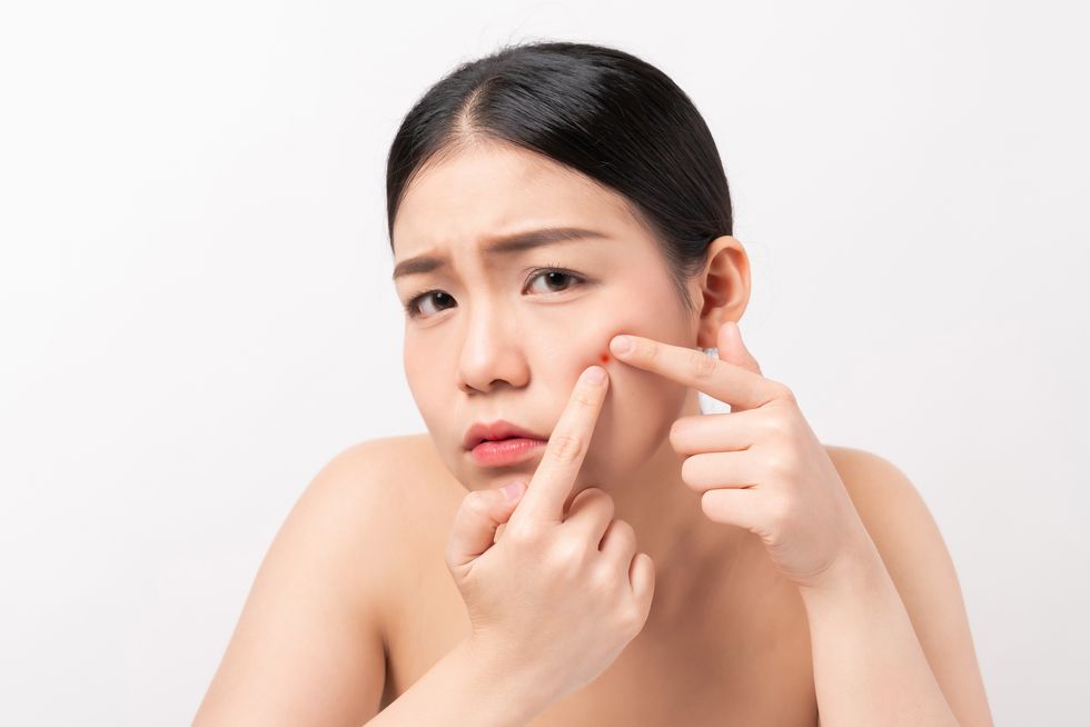 asian woman squeezing pimples on her face, skin care lifestyle concept