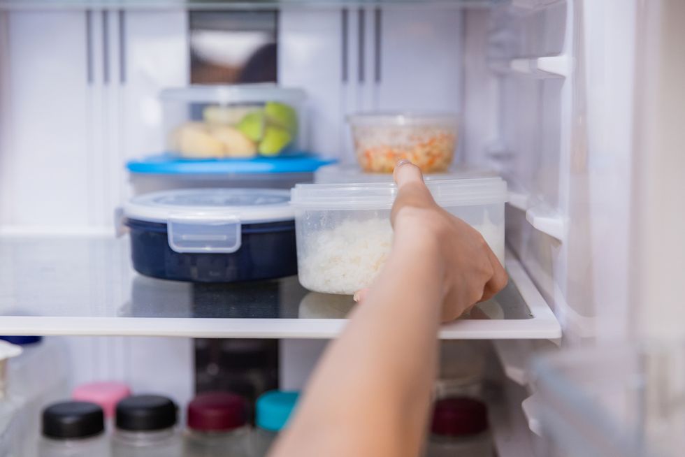 asian woman stored leftovers food in plastic container put into refrigerator