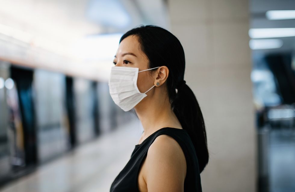 asian woman with protective face mask waiting for subway mtr train in platform