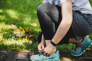 asian woman working out in a park, tying shoelace