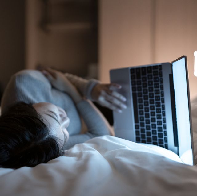 asian woman working with laptop on the bed