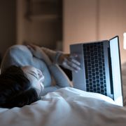 asian woman working with laptop on the bed