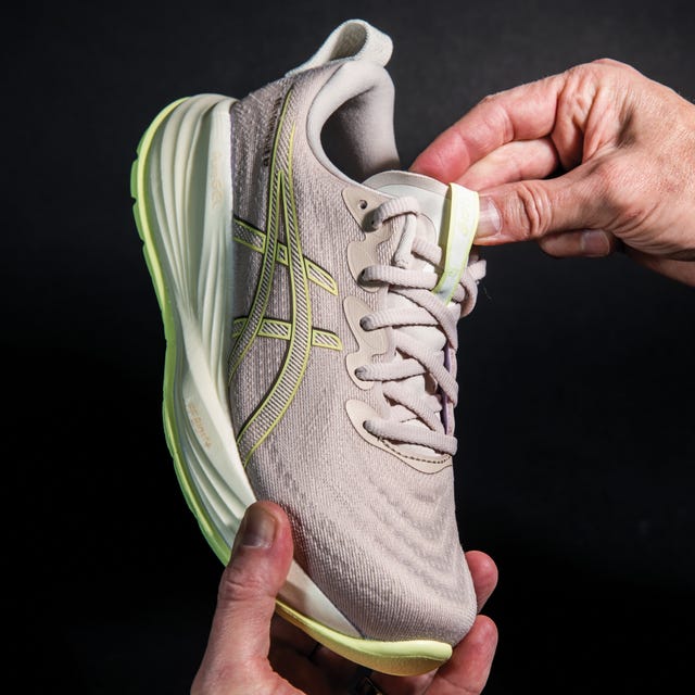 athletic shoe being held and adjusted showcasing its features