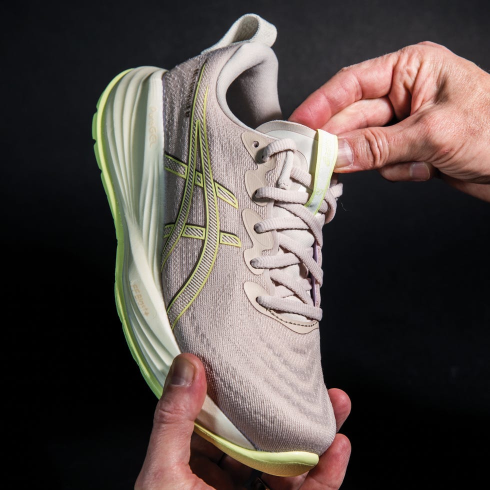 athletic shoe being held and adjusted showcasing its features