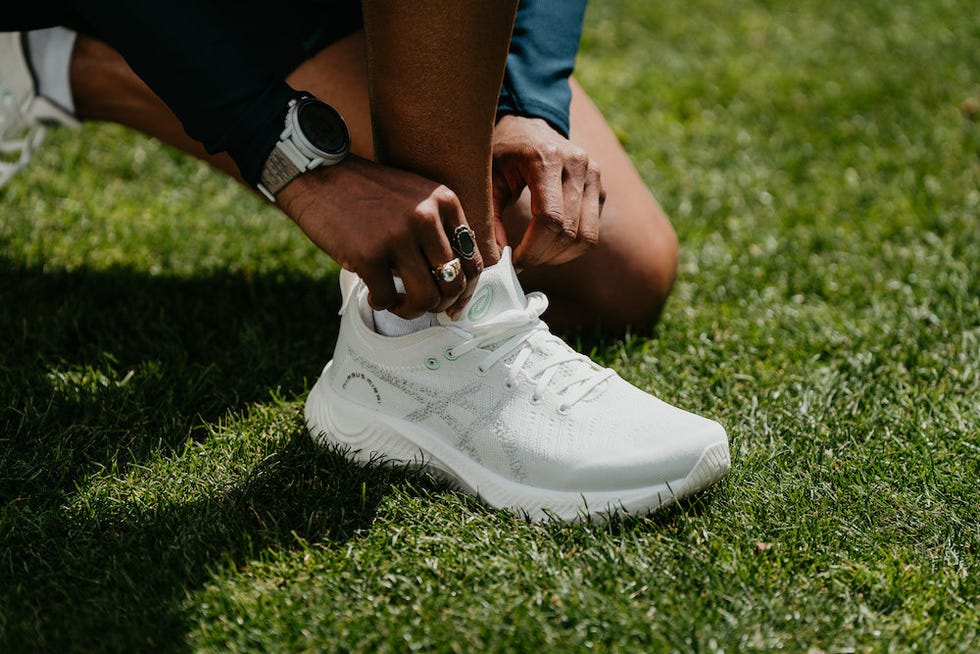 a person's feet in white shoes on grass