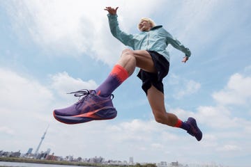 a person is performing a jump, dressed in a light blue athletic jacket and dark shorts their legs are extended in mid air, showcasing purple athletic shoes and vibrant socks