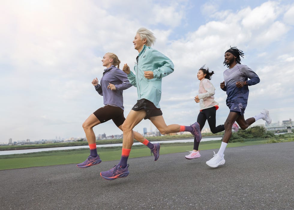 four individuals are engaged in a running activity along a flat, paved pathway