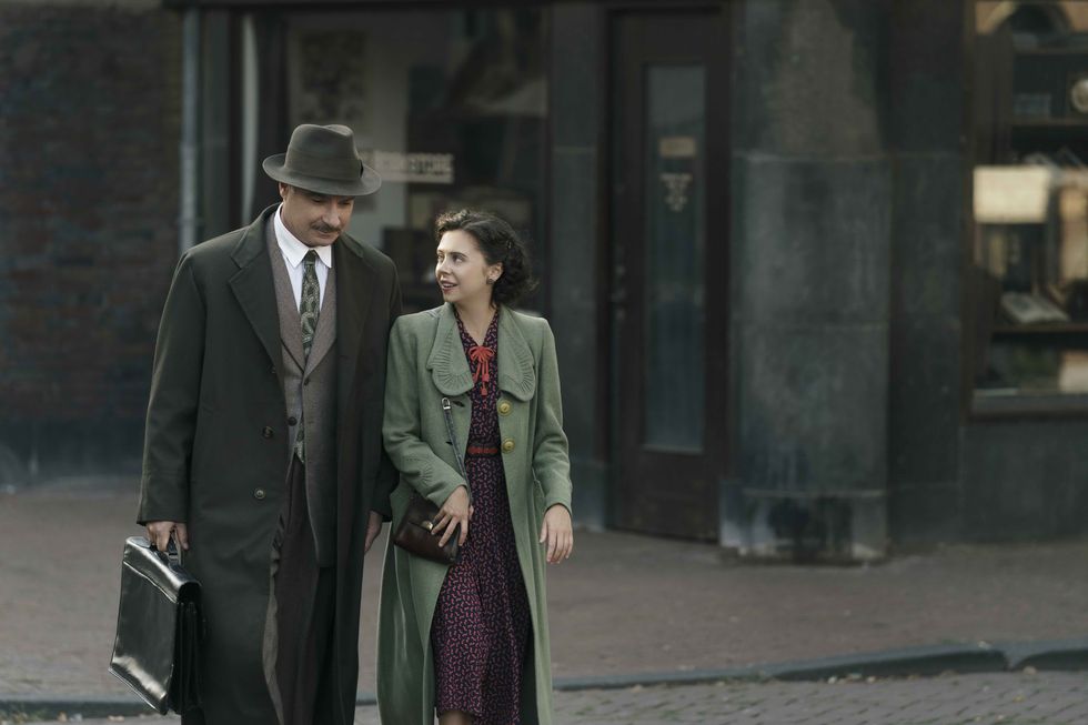 otto frank, played by liev schreiber, walks with miep gies, played by bel powley in a small light photo credit national geographic for disneydusan martincek