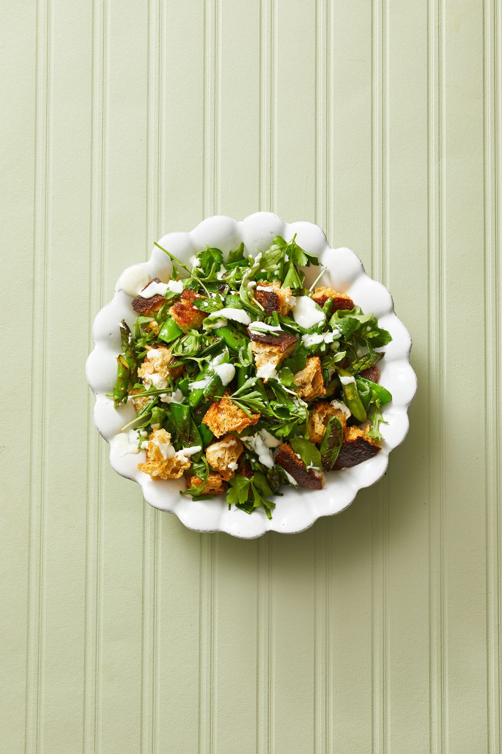 asparagus and pea panzanella in a white bowl