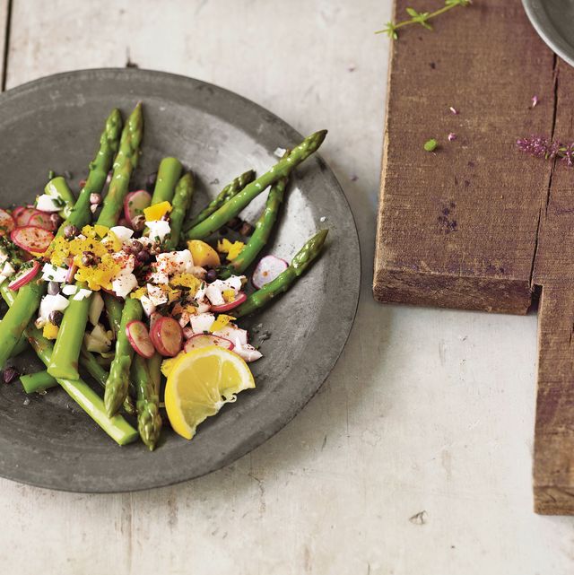 asparagus salad in a gray bowl next to a cutting board