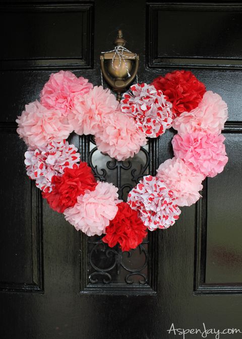 heart shaped wreath made out of flowers made from pink, red and patterned valentine's tissue hanging on a door