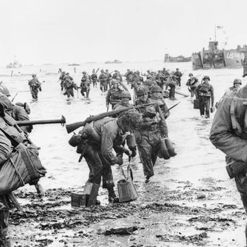 soldiers carrying guns and supplies onto the shore during the land invasion at omaha beach