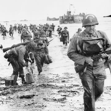 soldiers carrying guns and supplies onto the shore during the land invasion at omaha beach