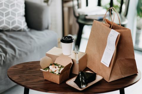 assorted fresh and healthy takeaway meals delivered at home, with healthy grilled chicken vegetable salad, japanese style rice ball  onigiri and a cup of coffee freshly served on the coffee table