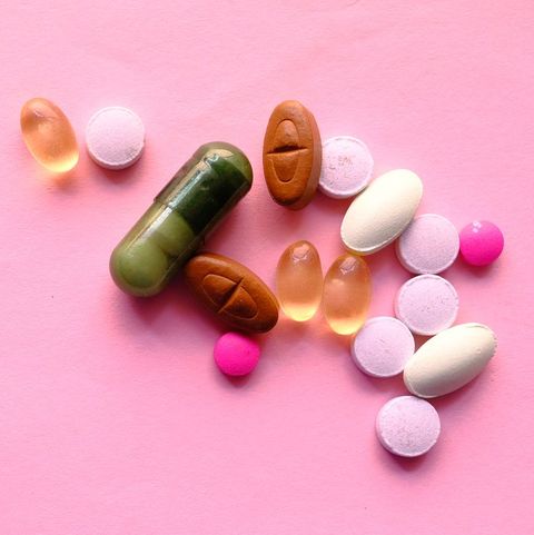 Assorted pharmaceutical medicine pills, tablets and capsules over pink background
