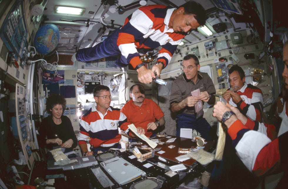 Astronauts And Cosmonauts About To Share A Meal