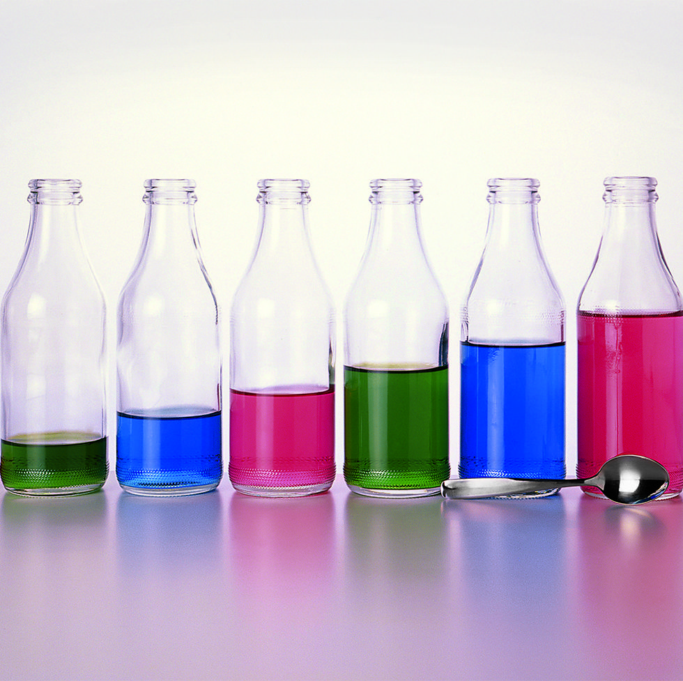 milk bottle xylophone consisting of seven bottles of varying amounts of coloured water and a metal spoon, in a row, as part of an at home science experiment