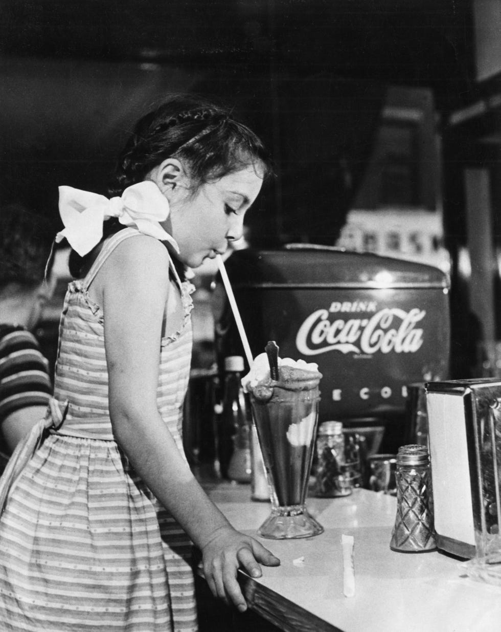little girl eats large milkshake
