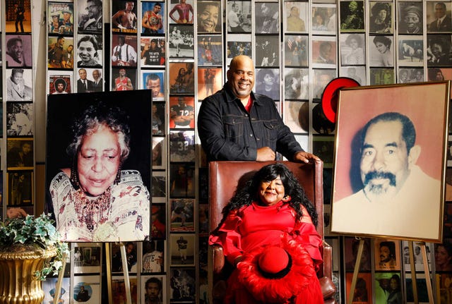 mona vaughn scott ,seated, the black repertory group’s executive director and artistic director, and her son, sean vaughn scott, the theater company’s development director, are flanked by photos of their parents and grandparents, respectively, the organization’s founders