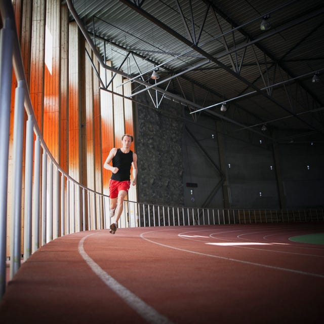 un hombre corre por una pista cubierta de atletismo