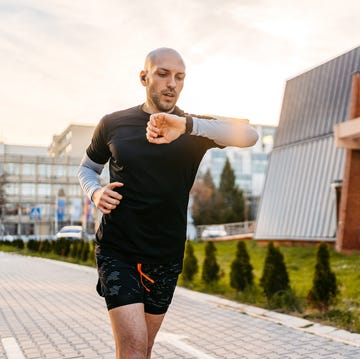 Athlete Checking Fitness Activity On Fitness Tracker While Running Outdoors athlete checking fitness activity on fitness tracker while running outdoors