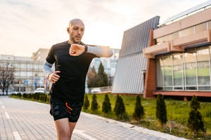 athlete checking fitness activity on fitness tracker while running outdoors