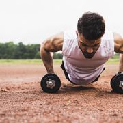 athlete doing pushups with dumbbells on sports field