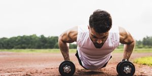 athlete doing pushups with dumbbells on sports field
