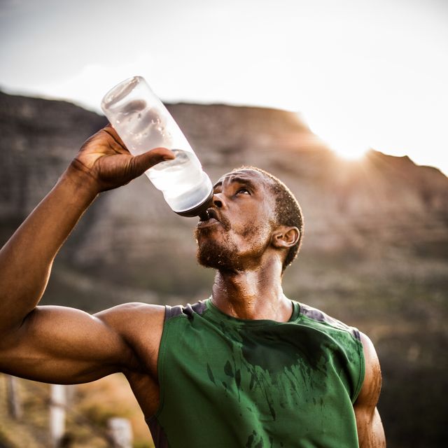 athlete drinking thirstily from a water bottle outdoors