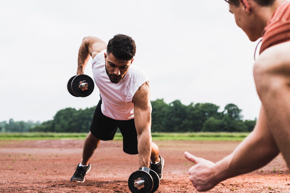 atleta ejercitándose con pesas en una pista deportiva