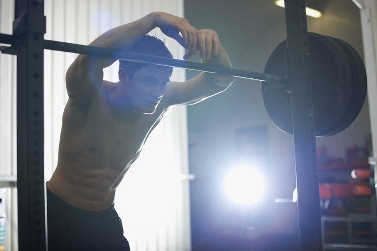athlete leaning on barbells in gym athlete leaning on barbells in gym
