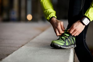 een hardloper strikt de veters van zijn schoen voor het lopen