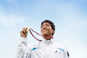 athlete smiling on podium with the medal