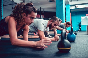 athletes practicing plank exercise with kettlebells