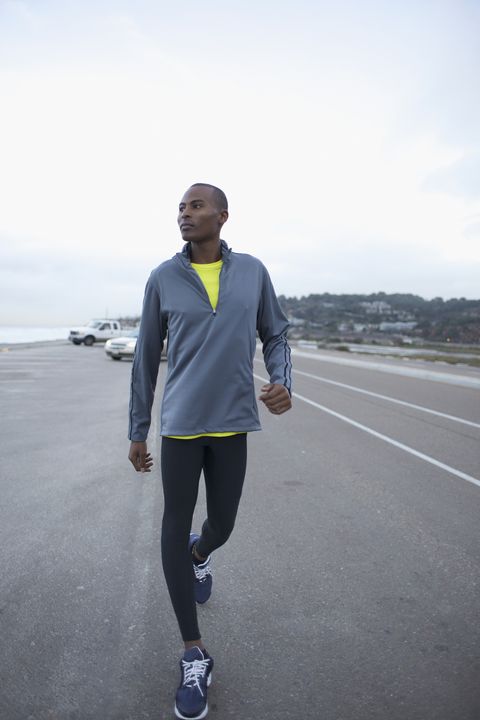 athletic black man walking along road