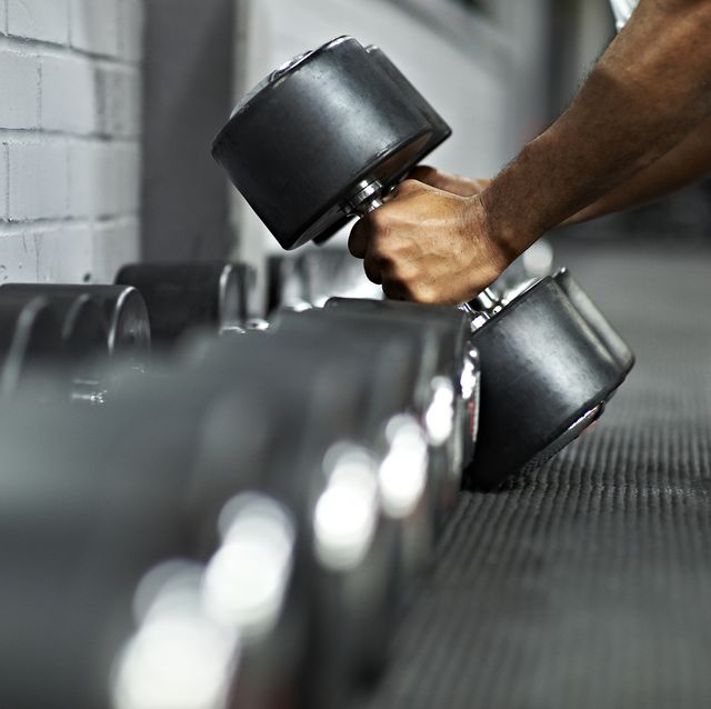 athletic male picking up dumbbells in gym
