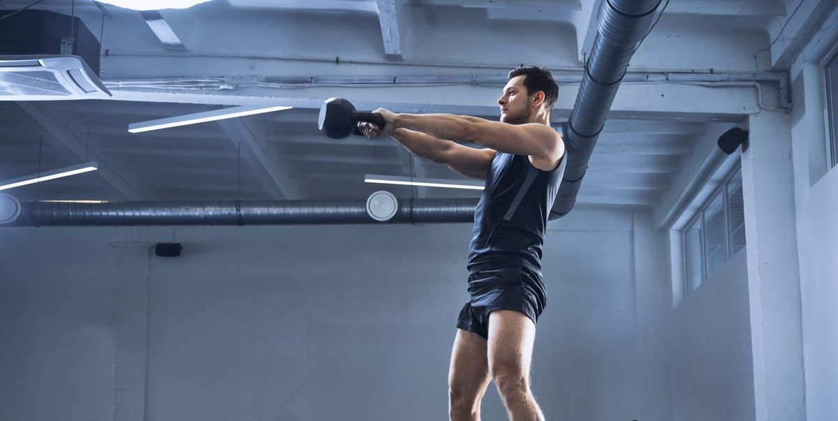 athletic man doing kettlebell swing exercise at gym