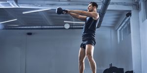 Athletic man doing kettlebell swing exercise at gym