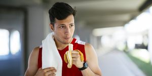 athletic man eating banana after workout outdoors